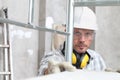 Man work, professional construction worker with scaffolding, safety hard hat, hearing protection headphones, gloves and
