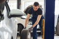 Man in work uniform changing car wheel indoors. Conception of automobile service Royalty Free Stock Photo