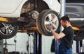 Man in work uniform changing car wheel indoors. Conception of automobile service Royalty Free Stock Photo