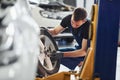 Man in work uniform sitting and changing car wheel indoors. Conception of automobile service Royalty Free Stock Photo