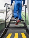 Man worker in blue overal and safety shoes walking upnstairs on steel stairs Royalty Free Stock Photo