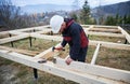 Man worker building wooden frame house on pile foundation. Royalty Free Stock Photo