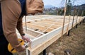 Man worker building wooden frame house on pile foundation. Royalty Free Stock Photo