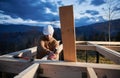 Man worker building wooden frame house on pile foundation. Royalty Free Stock Photo