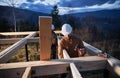 Man worker building wooden frame house on pile foundation. Royalty Free Stock Photo