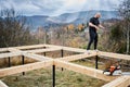 Man worker building wooden frame house on pile foundation. Royalty Free Stock Photo