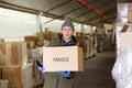 Man worker carrying cardboard box with fragile content