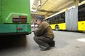 Man worker conducting technical inspection for trolleybus parked at the trolley depot hangar, depot maintenance. Kiev
