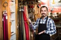 man worker displaying various belts in leather workshop