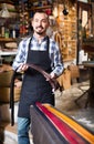 man worker displaying various belts in leather workshop