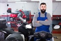 Man worker displaying various motorcycles in workshop Royalty Free Stock Photo