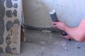 Man worker fills crack between wall and cement floor with mounting foam in room.