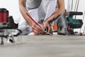 Man worker hands installing timber laminate floor, takes measurement with the tape measure and pencil. Wooden floors house renovat