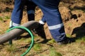 Man worker holding pipe, providing sewer cleaning service outdoor. Sewage pumping machine is unclogging blocked manhole