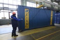 Man worker lifting cargo container for repairing using the hoist crane. Maintenance hall for repairing containers