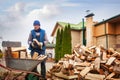 A man worker loads firewood into a wheelbarrow for heating the house,