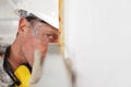 Man worker measure angle of wall with square wear hard hat, glasses and hearing protection headphones, at interior construction