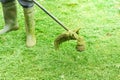 Man or worker mowing the green grass. Gardener mows weeds with electric or petrol lawn trimmer in city park or backyard. Gardening Royalty Free Stock Photo