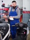 Man worker offering scooters in motorcycle workshop Royalty Free Stock Photo