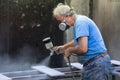 Man worker painting wooden board with spray gun