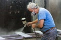 Man worker painting wooden board with spray gun