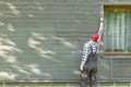 Man worker painting wooden house exterior wall with paintbrush and wood protective color Royalty Free Stock Photo