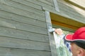 Man worker painting wooden house exterior wall with paintbrush and wood protective color Royalty Free Stock Photo