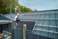 Man worker prepearing for mounting photovoltaic solar modules on roof of house. Royalty Free Stock Photo