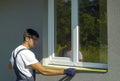 Man worker in safety glasses cleaning surface for PVC window metal sill installation