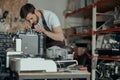 Man worker in uniform checking coffee machine in own workshop Royalty Free Stock Photo