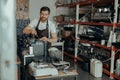 Man worker in uniform checking coffee machine in own workshop and looking camera Royalty Free Stock Photo