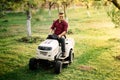 Man worker using ride on lawnmower, male riding lawn tractor and relaxing during sunset golden hour Royalty Free Stock Photo