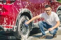 Man worker washing car`s alloy wheels on a car wash. Car wash with soap. Royalty Free Stock Photo