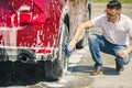 Man worker washing car`s alloy wheels on a car wash. Car wash with soap. Royalty Free Stock Photo