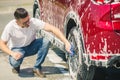 Man worker washing car`s alloy wheels on a car wash. Car wash with soap. Royalty Free Stock Photo