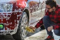 Man worker washing car`s alloy wheels on a car wash Royalty Free Stock Photo