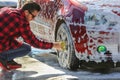 Man worker washing car`s alloy wheels on a car wash Royalty Free Stock Photo