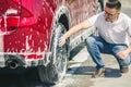 Man worker washing car`s alloy wheels on a car wash. Car wash with soap. Royalty Free Stock Photo