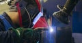 A man worker welding the seams between the metal beams indoors