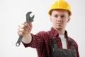 A man, a worker, in a yellow helmet, in a working overalls and a red checkered shirt, is holding a steel adjustable Royalty Free Stock Photo