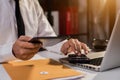 The man working on calculator to calculate financial data report, accountancy document and laptop computer at office. Royalty Free Stock Photo