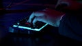 A man working at a computer, close-up of hands and neon glowing keyboard