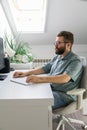 Man working at computer desk under skylight. Representation of focus, productivity, and modern remote work routine in bright home Royalty Free Stock Photo