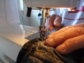 Man working with an electrical sewing machine in a home business, fixing jeans, close up view