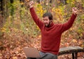 Man working freelance on laptop sitting outdoors on the park bench in the autumn forest Royalty Free Stock Photo