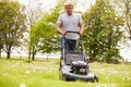 Man Working In Garden Cutting Grass With Lawn Mower Royalty Free Stock Photo