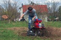 Man working in the garden with garden tiller. tractor cultivating and loosens soil field