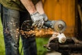 Man working with grinder saw, close up view on tool. Electric saw and hands of worker with sparks. Worker cutting metal