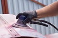 A man working with grinding tool. Sanding of car elements. Hands in black gloves hold a power tool. Royalty Free Stock Photo
