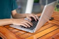 A man working on his laptop, typing on the laptop keyboard, sitting at an outdoor table of a cafe Royalty Free Stock Photo